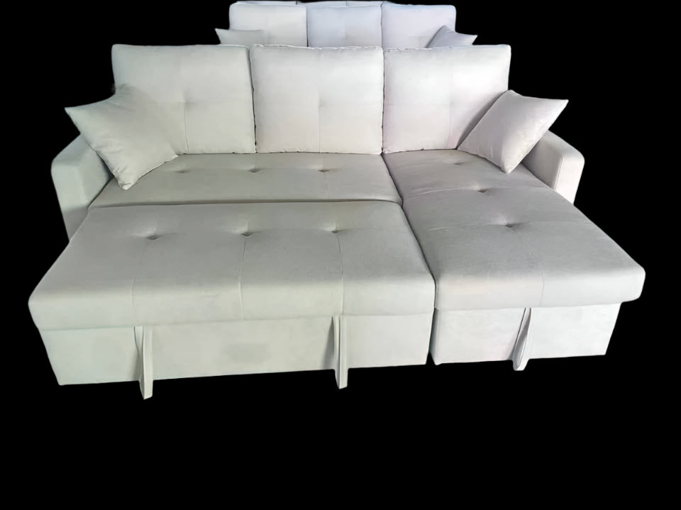 Beige sectional sofa with storage ottoman on a green floor.