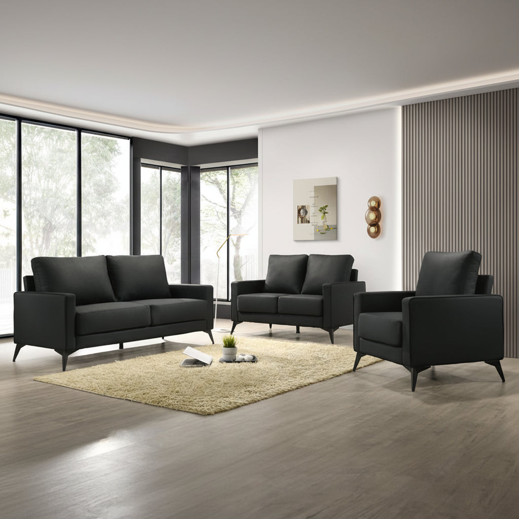 A modern black leatherette sofa set, including a sofa, loveseat, and chair, with pocket coil seating, displayed in a room with a light-colored carpet and large windows.