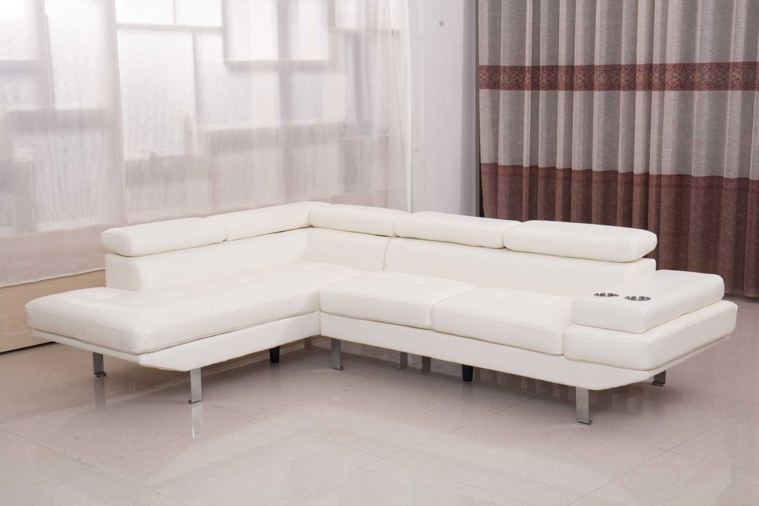 A white air leather sectional sofa with a modern sleek design, positioned in a bright room with a transparent curtain background.