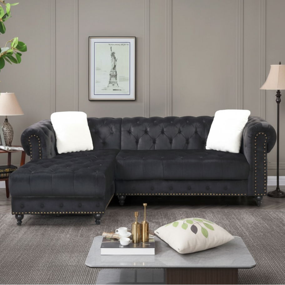 Black tufted sectional sofa in a living room setting with decor elements.