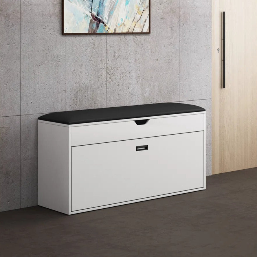 White storage bench with black top against a gray tiled wall with abstract art.