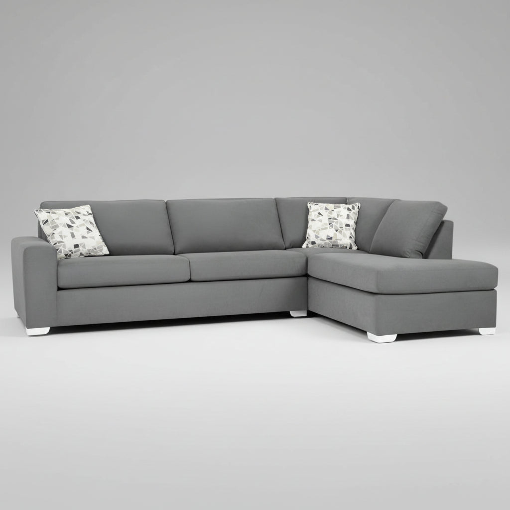 A gray fabric sectional sofa with a left-hand face chaise, pillows on the sofa, set against a room with windows and decorative items.
