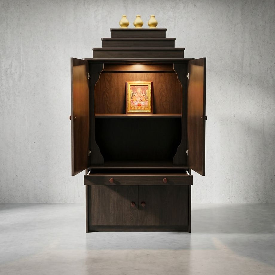 A dark brown wooden altar cabinet with its doors open, showcasing a tiered top with three gold vases, a central shelf with a framed picture, and a lower drawer compartment. The cabinet is set against a textured gray concrete wall and floor.
