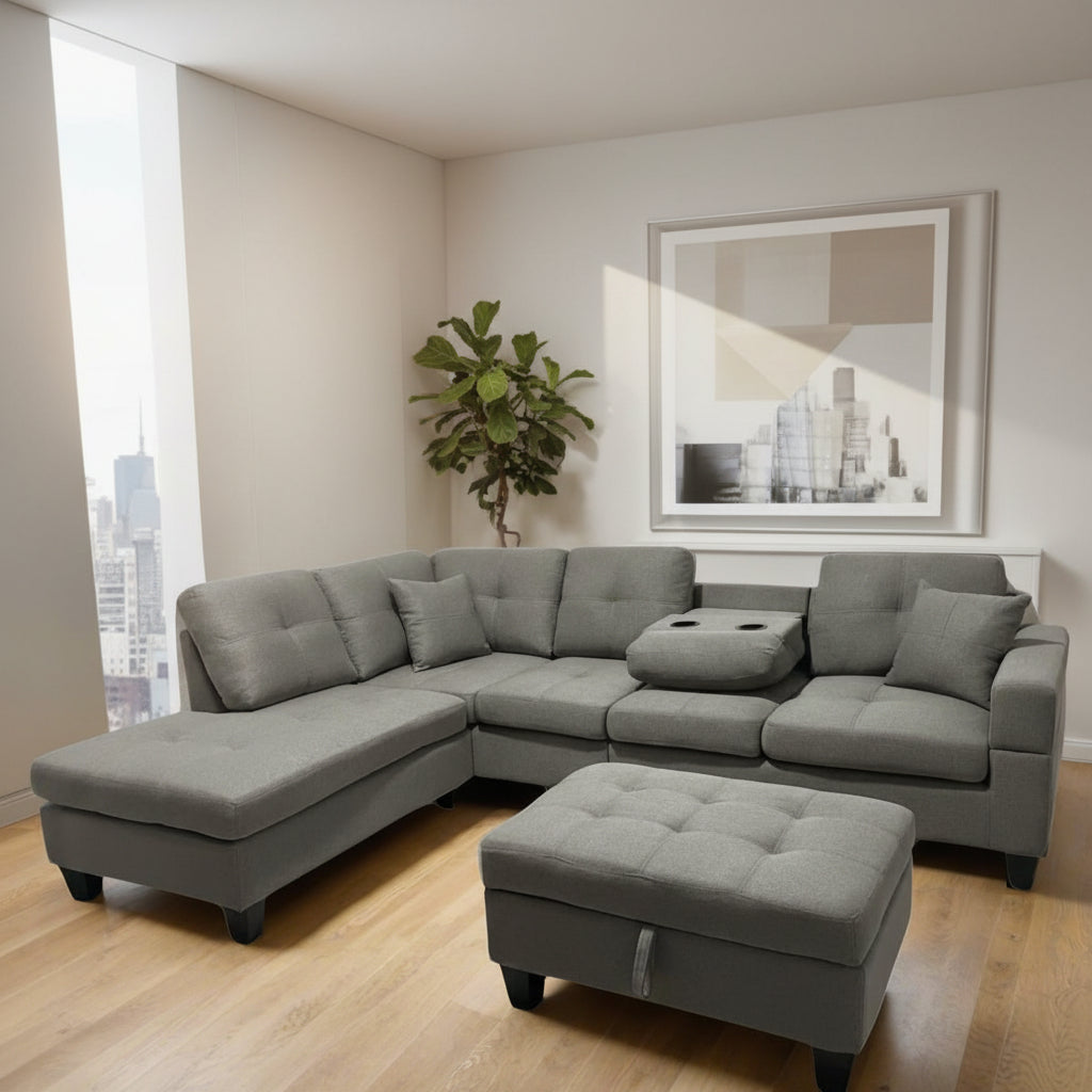 A grey reversible sectional sofa with a chaise on one end and a square storage ottoman in a matching color. The sectional has several cushions on it, and the ottoman is placed on a hardwood floor against a wall.